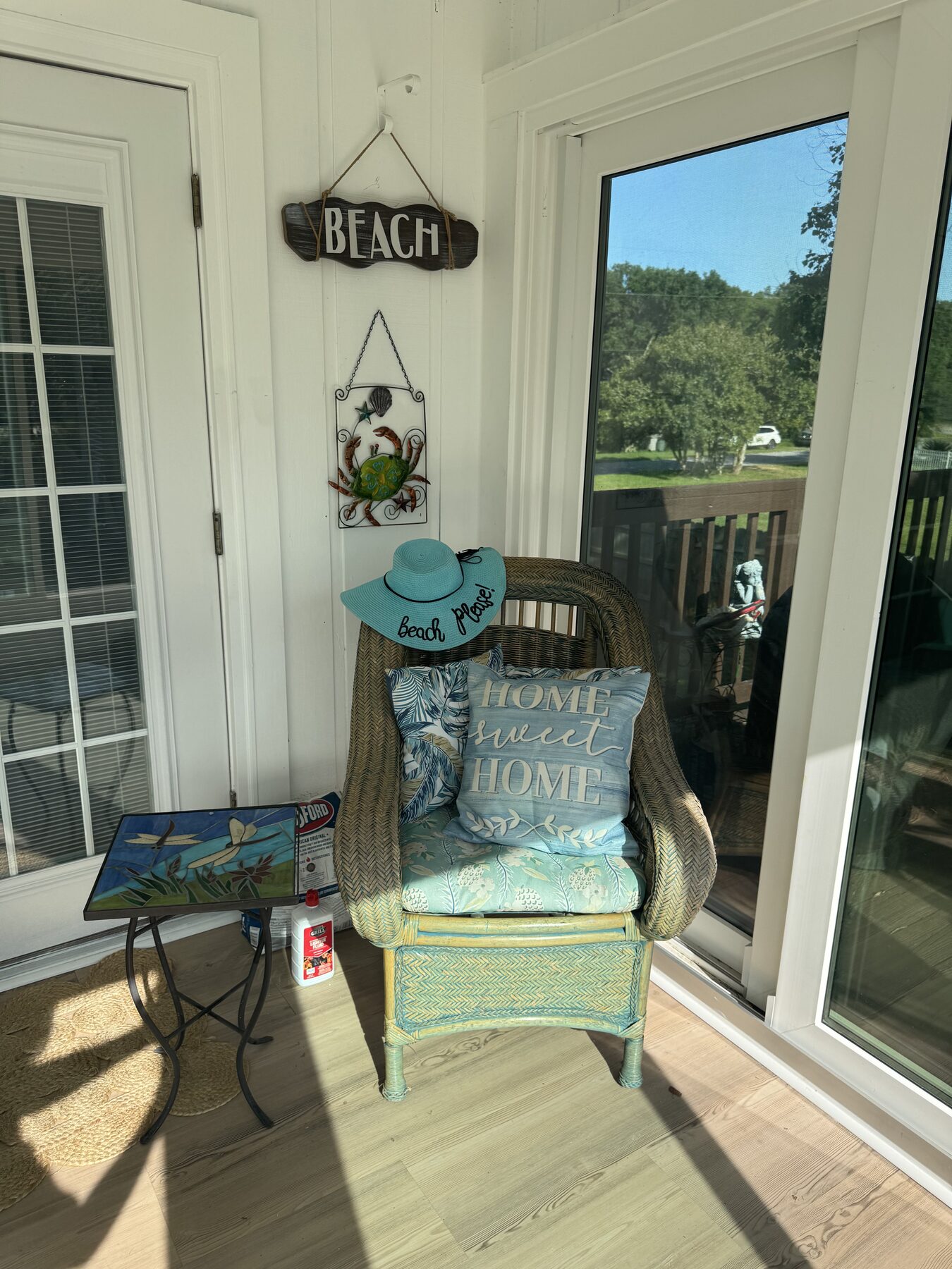 Cozy wicker reading chair with 'Home Sweet Home' pillow and a 'Beach' sign, tucked into a sunny corner of the Florida room