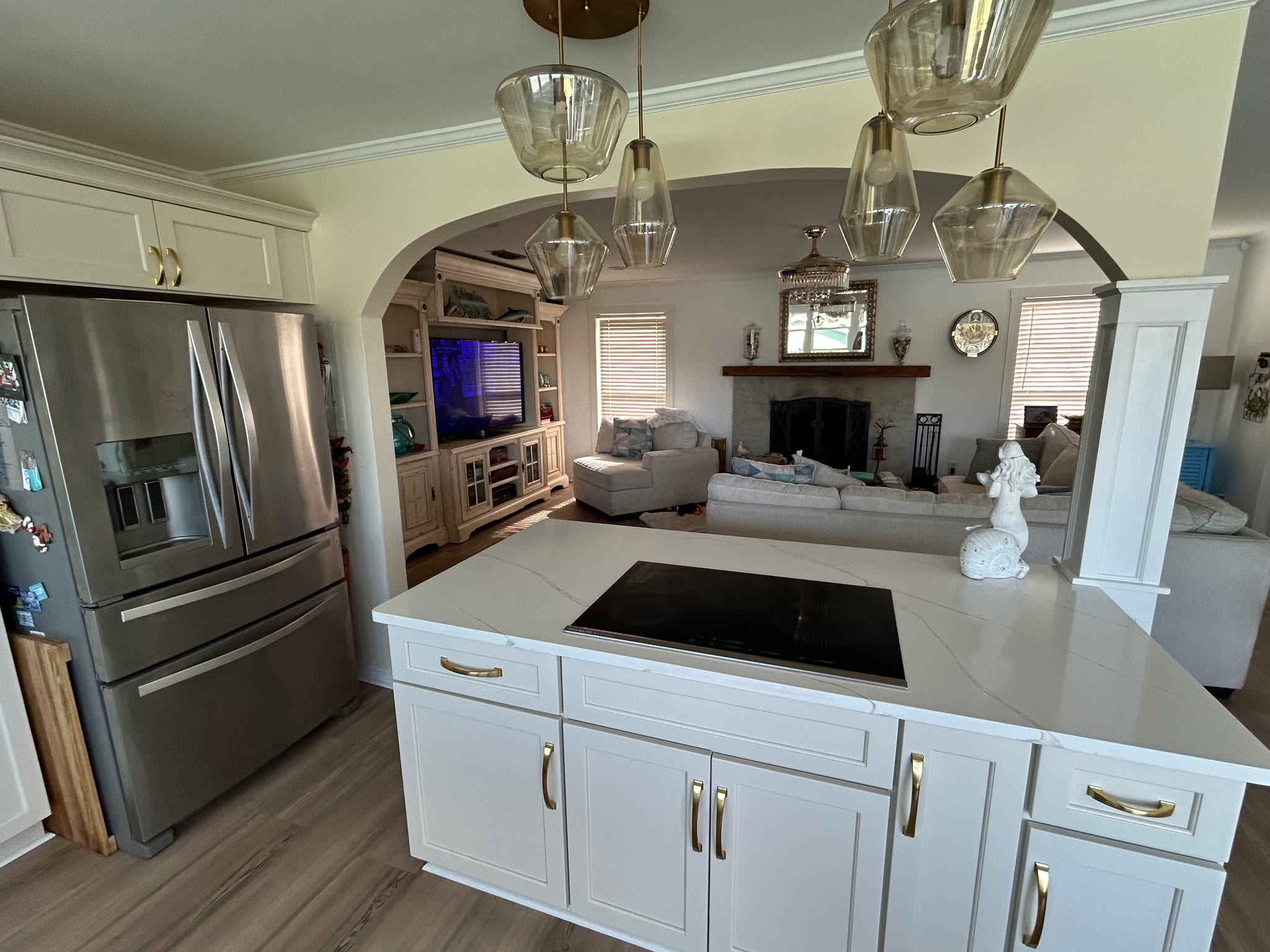 View across the kitchen island into the living room with sectional sofa, entertainment center, and fireplace