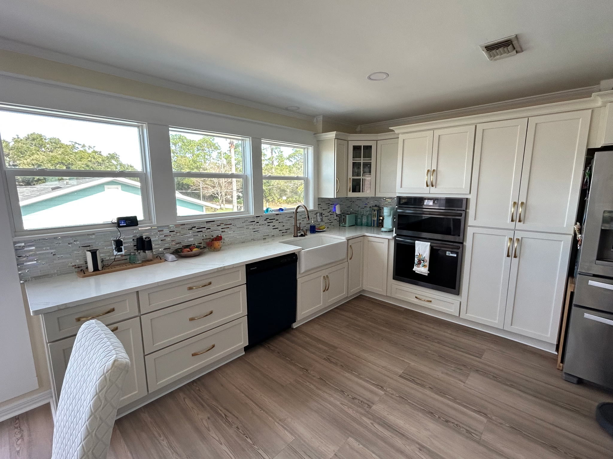 Kitchen counters and cabinets with tile backsplash and windows looking out over the neighborhood