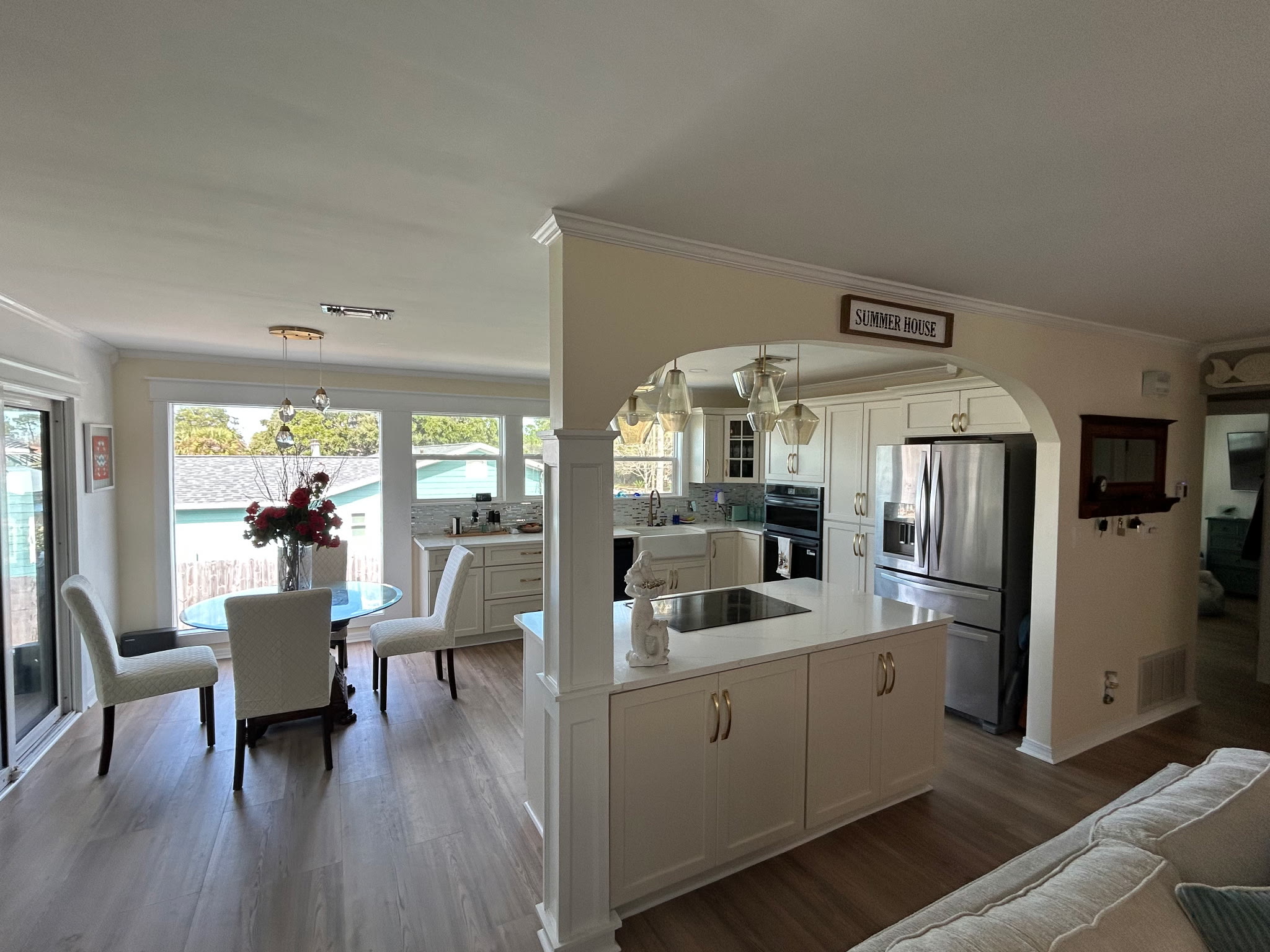 Bright dining nook with a round glass table and upholstered chairs beside the open kitchen