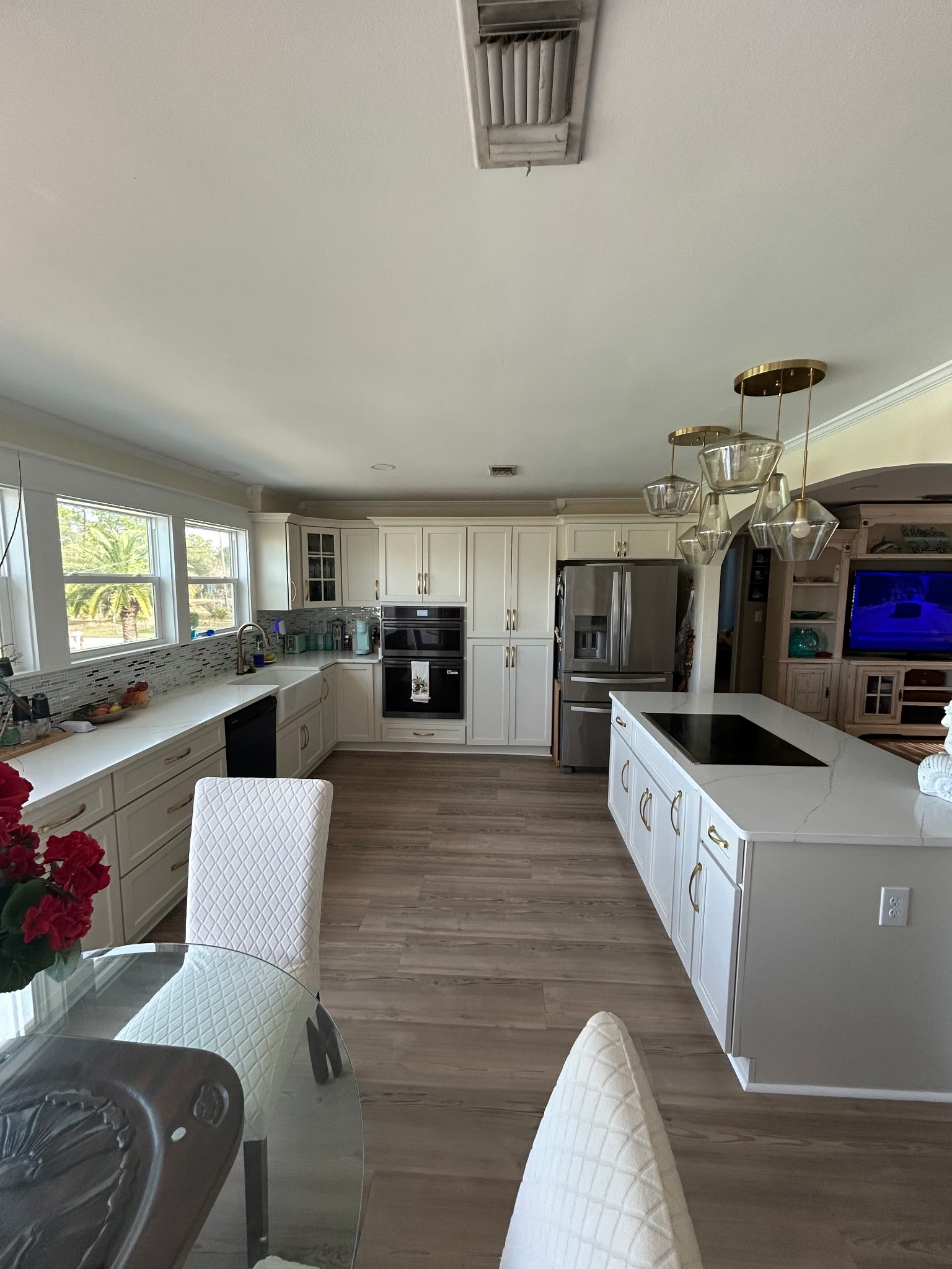 Wide view of the kitchen with white cabinetry, quartz counters, and brass pendant lights over the island