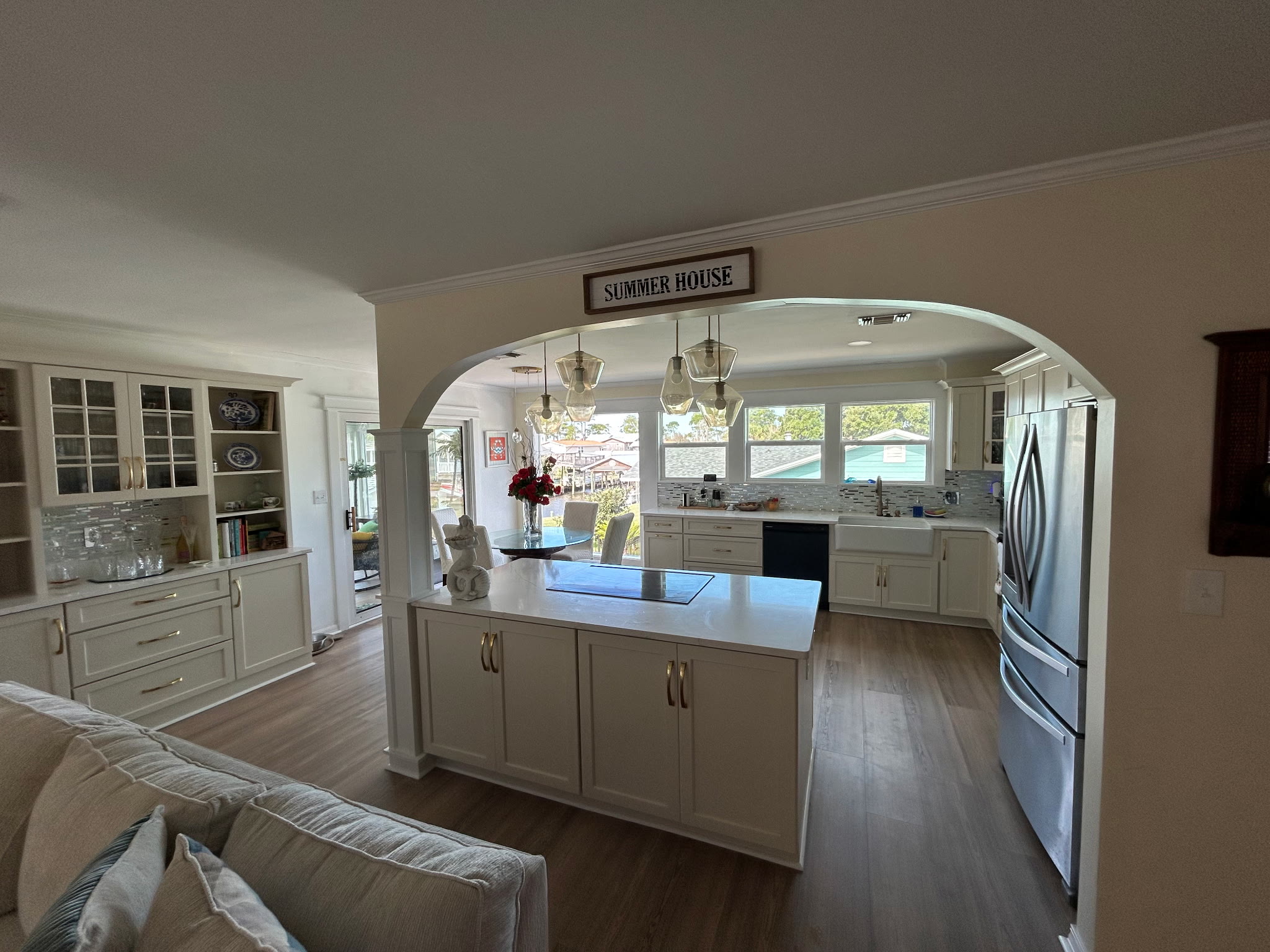 Open living area with a Summer House sign above the arched kitchen entry, looking through to the dining table and canal-side windows