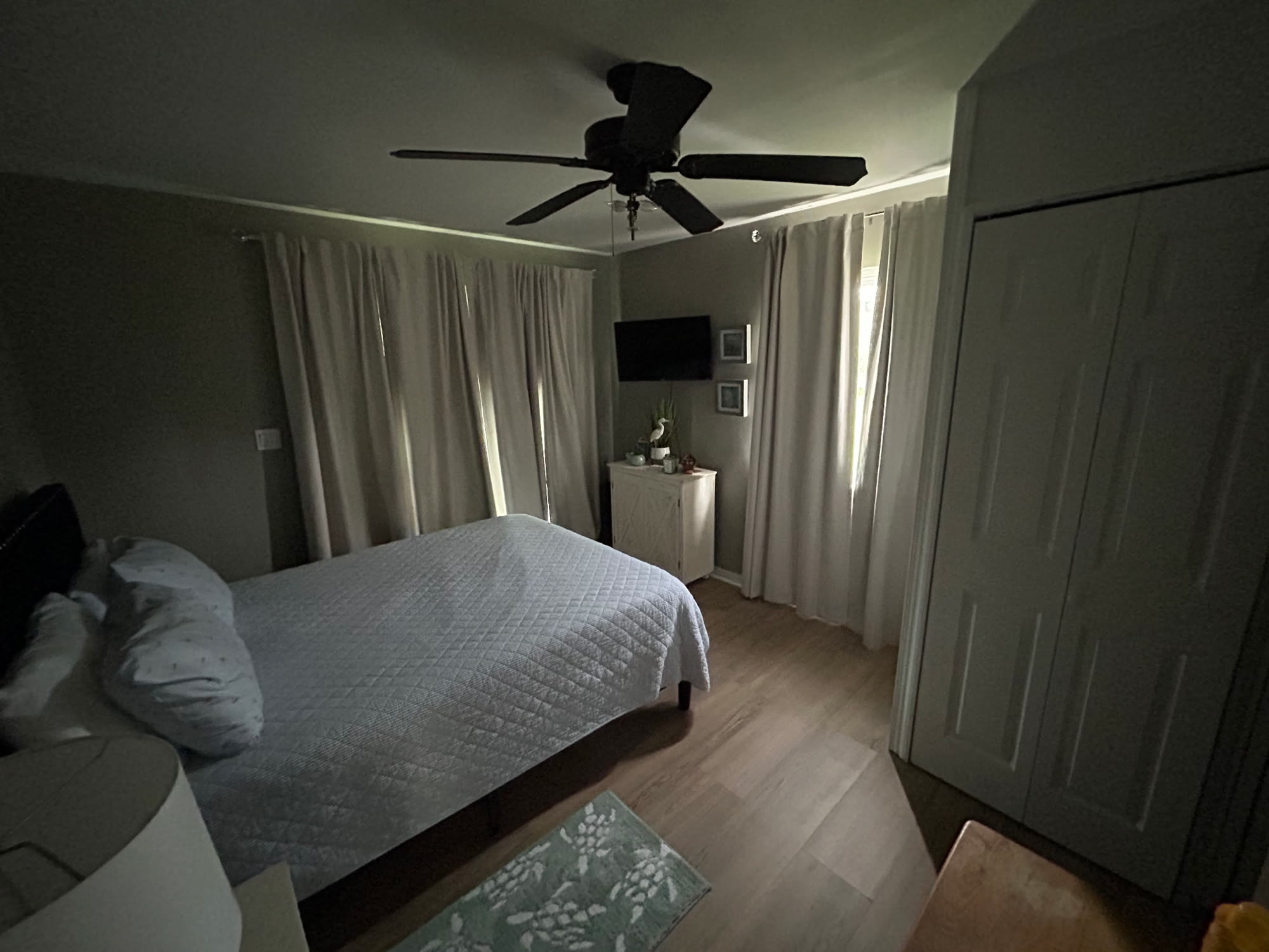 Upstairs second bedroom with a quilted white bedspread, curtained windows, TV, and closet